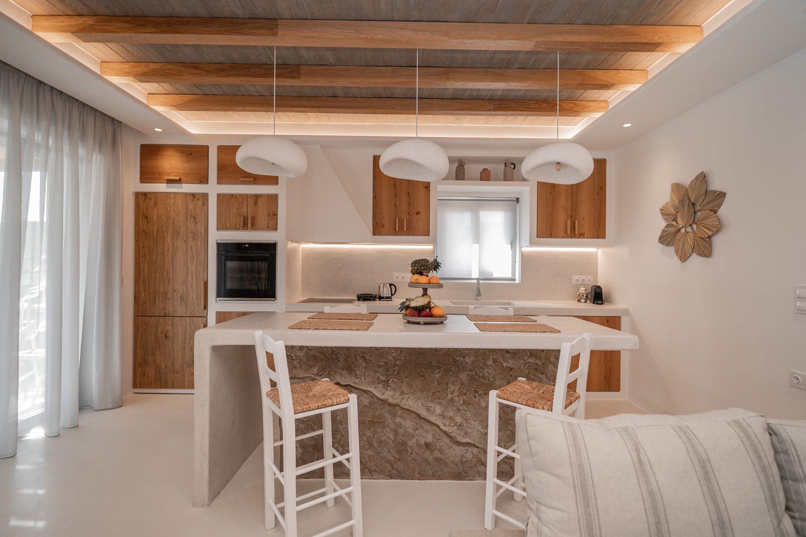 Kitchen of Villa A in Naxos with a marble-topped island, oak cabinetry and bar stools
