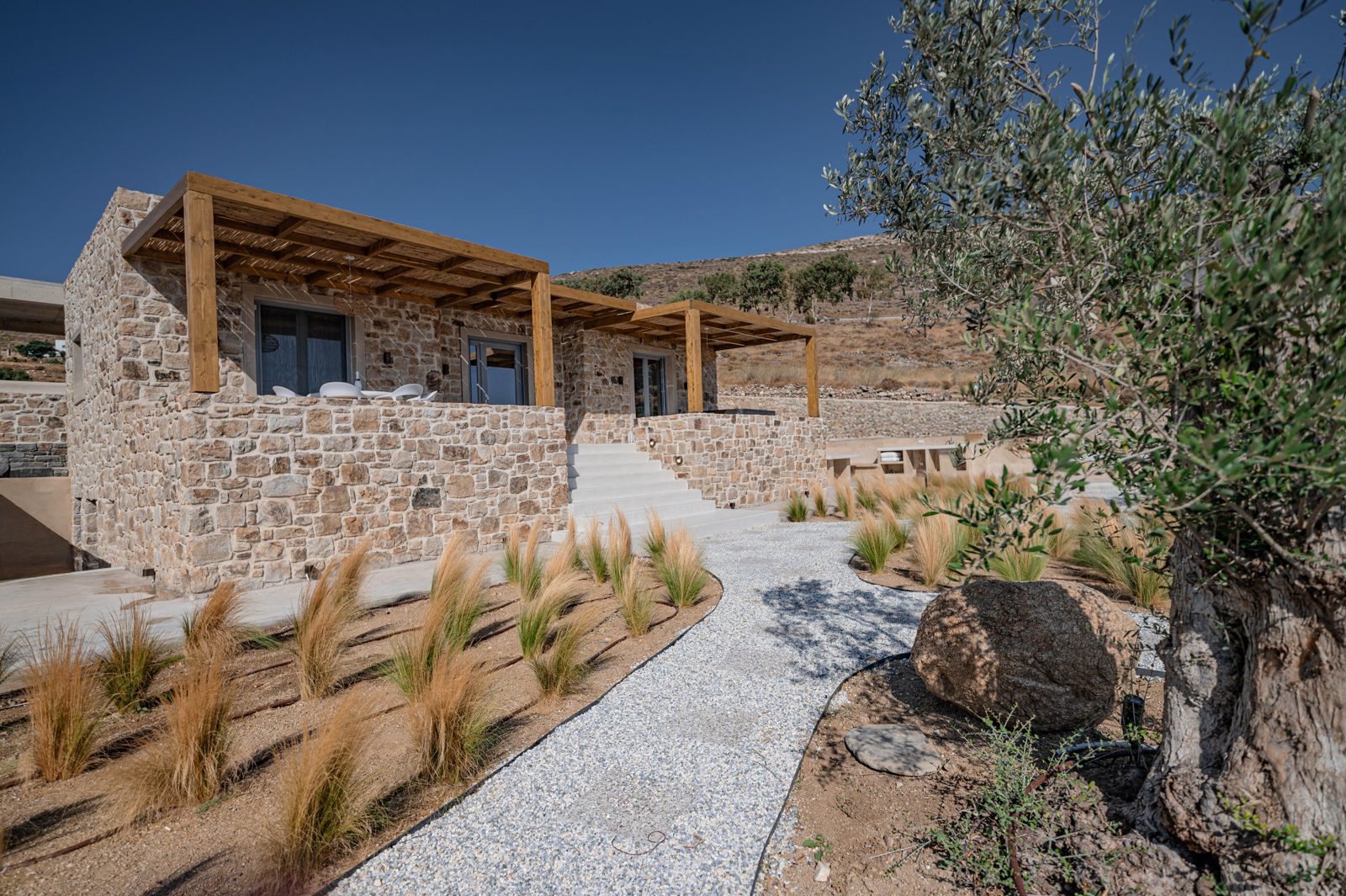 Side view of Villa A in Naxos showing the dry-stone facade and shaded timber pergola