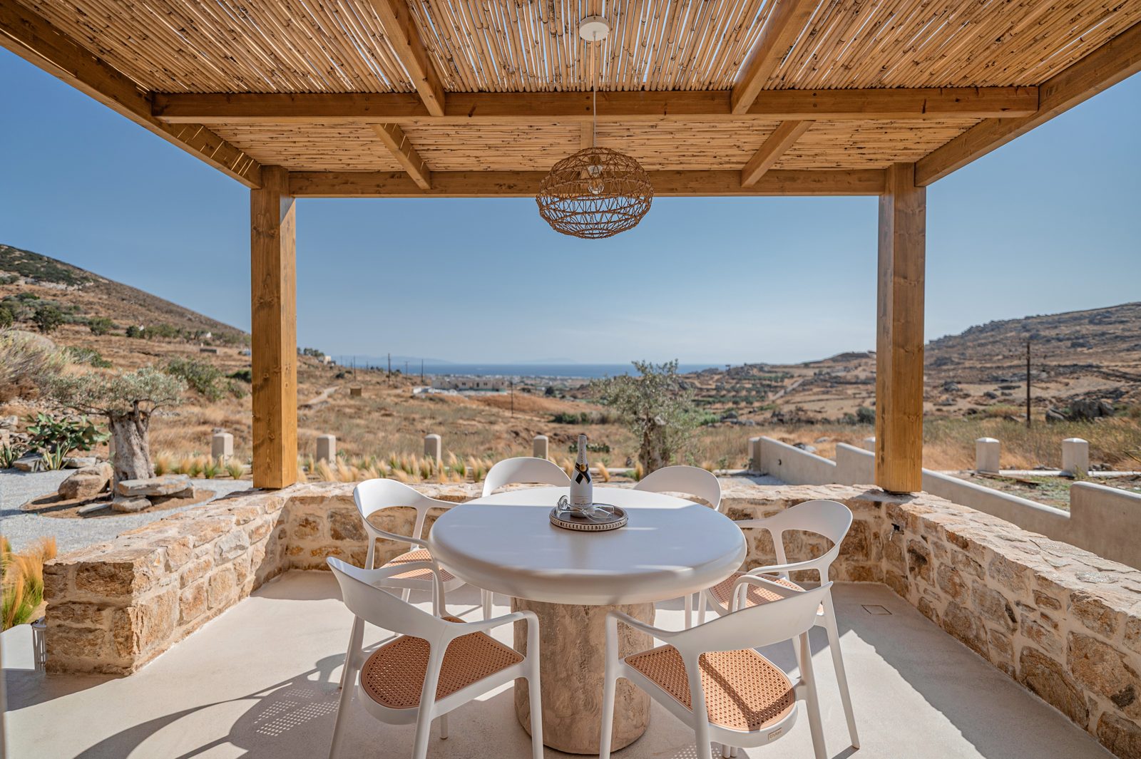 Shaded stone terrace of a Naxos villa with a dining table and sea view